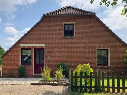 ein rotes Backsteinhaus mit einem Zaun davor in der Unterkunft Paradiesje in Leer