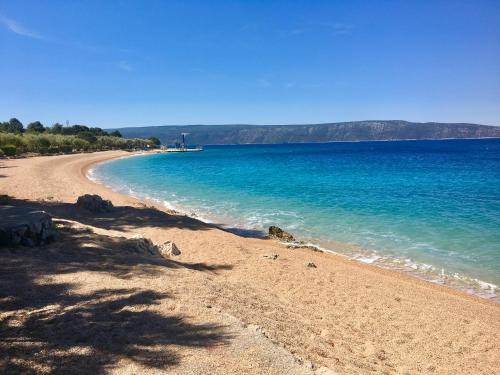a sandy beach with blue water on a sunny day at Naomi's Sunshine in Cres