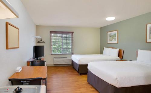 a hotel room with two beds and a sink at WoodSpring Suites Louisville Southeast in Louisville
