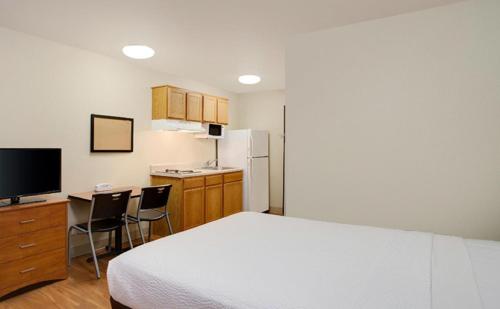 a bedroom with a bed and a desk and a kitchen at WoodSpring Suites Louisville Southeast in Louisville