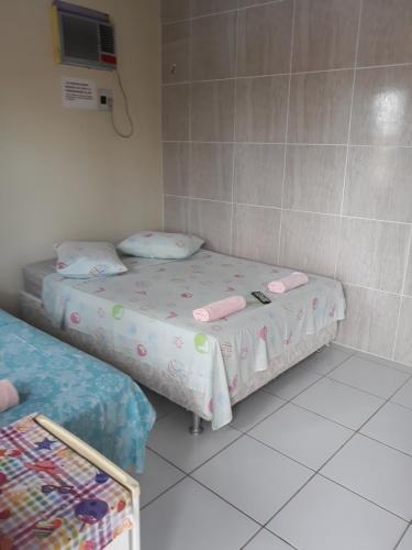 a room with two beds and a tv on the wall at Pousada Sossego Salinas in Salinópolis