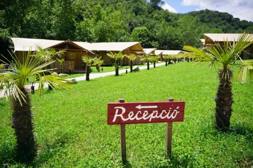 a sign in front of a resort with palm trees at Glamping Can Bora Lodges in Las Serras