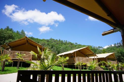 a view of a resort with umbrellas and trees at Glamping Can Bora Lodges in Las Serras