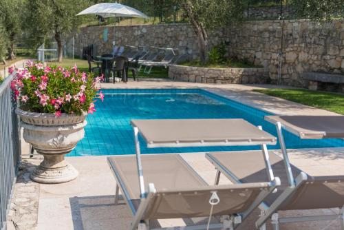 een zwembad met twee stoelen en een tafel en een pot bloemen bij Agricampeggio Relax Maxicaravan in Castelletto di Brenzone