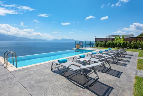 een groep ligstoelen naast een zwembad bij Ionian Heaven Villas in Nikiana