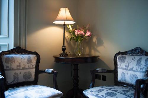 two chairs and a table with a lamp and a vase of flowers at No11 Boutique Hotel & Brasserie in Edinburgh