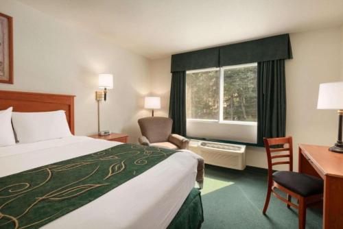 a hotel room with a bed and a desk and a window at Travelodge by Wyndham Dunsmuir in Dunsmuir