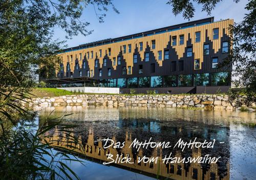a building with a reflection in a body of water at MY HOME MY HOTEL Rosenheim in Rosenheim