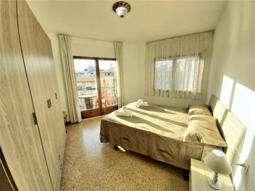 a bedroom with a bed and a large window at DIANA Apartamento con terraza muy cerca del mar in Pineda de Mar