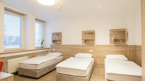 una camera con tre letti, un tavolo e finestre di A2 Boarding House Memmingen a Memmingen