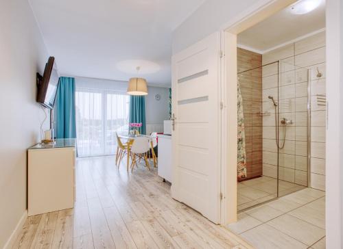 a bathroom with a shower and a kitchen with a table at Apartamenty Olivia in Władysławowo