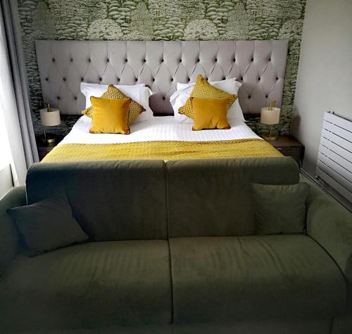 a bedroom with a bed with yellow pillows and a couch at Hatherley Manor Hotel & Spa in Gloucester