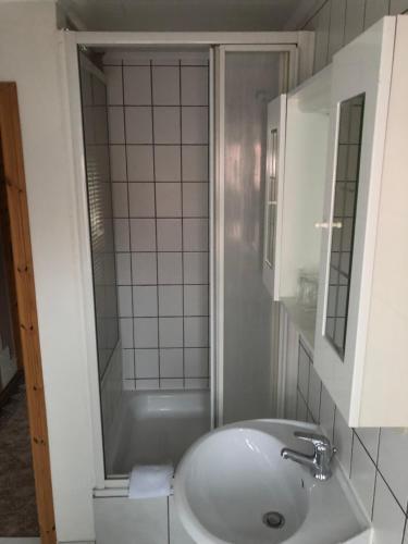 a white bathroom with a sink and a tub at Deutsches Haus in Neuhütte