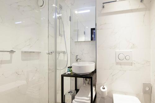 a white bathroom with a shower and a sink at Krisotel in Amsterdam