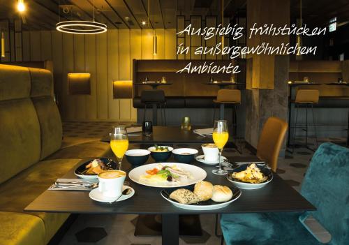 a table with plates of food and glasses of wine at MY HOME MY HOTEL Rosenheim in Rosenheim