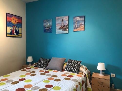 a bedroom with a bed and a blue wall with pictures at Avinguda de Pau Béjar in Vinaròs