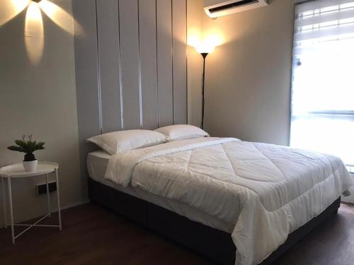 1 dormitorio con cama con edredón blanco y mesa en Homestay Fekrifarisha SA, en Shah Alam