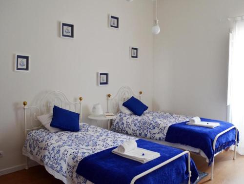 Dos camas en una habitación con sábanas azules y blancas. en Casa aOrta, en Faro