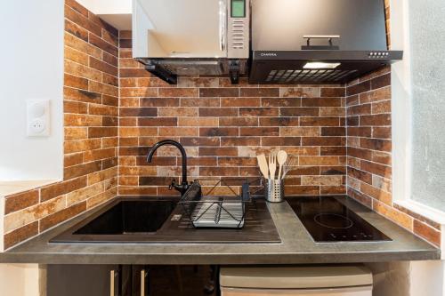 - une cuisine avec un évier et un mur en briques dans l'établissement VilleneuveCityStay Moderne, à Villeneuve-sur-Lot