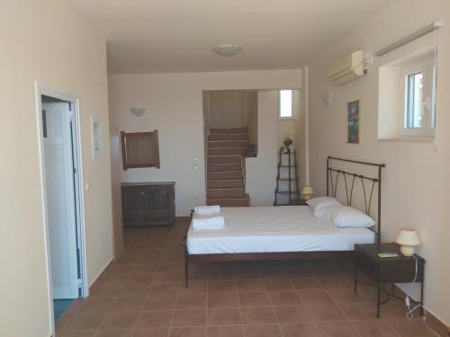 a bedroom with a bed with white sheets and a staircase at Neohori 3 in Stoupa