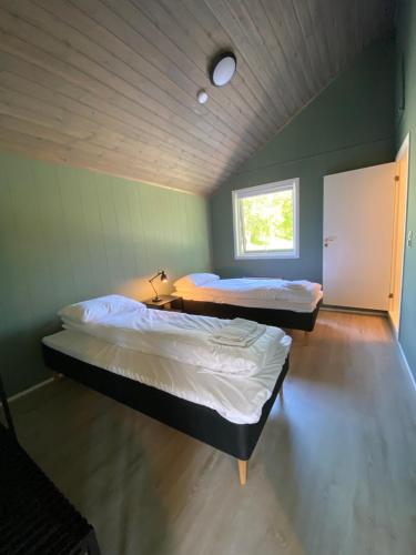 a bedroom with two beds and a window at Saltstraumen Hotels Hytter in Knapplund