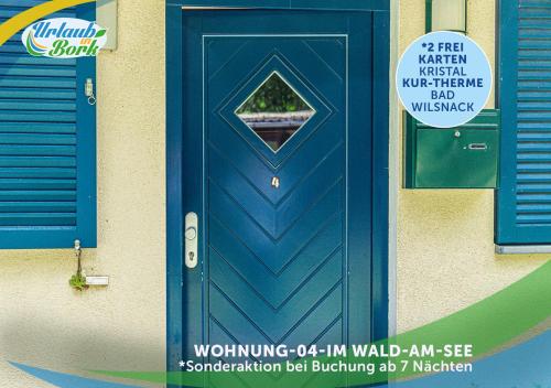 Une porte bleue sur un bâtiment avec un panneau. dans l'établissement Jagd-Angler-Suite-04-im-Wald-am-See, à Kyritz