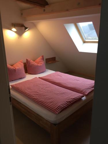 ein Bett mit roten Kissen in einem Dachzimmer in der Unterkunft Weingut Martin Schwarz in Meißen