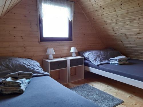 a bedroom with two beds and a window in a log cabin at Morska Fala in Jezierzany