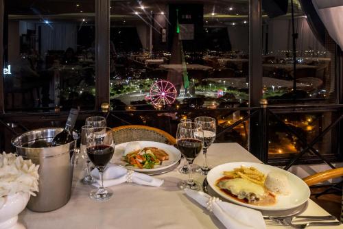 a table with two plates of food and glasses of wine at Golden Ingá Hotel in Maringá