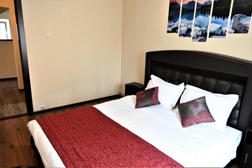 1 dormitorio con 1 cama con manta roja y almohadas en Marin Hotel Apartment en Braşov