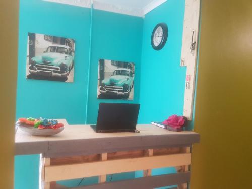 a desk with a laptop and pictures of a car on the wall at SURVIVOR GUEST HOUSE-Giyani in Giyani