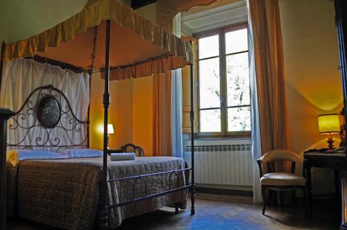 a bedroom with a canopy bed and a desk at Hotel Villa Casalecchi in Castellina in Chianti
