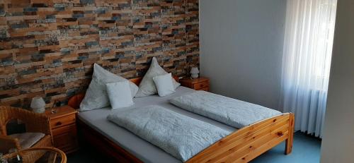 a bed in a bedroom with a brick wall at Gästezimmer Elly Dostert in Trittenheim