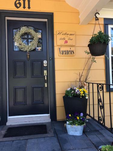 a black door on a yellow house with flowers at The Stella Rose B&B in Wolfville