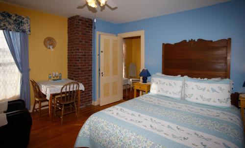 a bedroom with a bed and a table with a chair at À Amour et Amitié in Magog-Orford