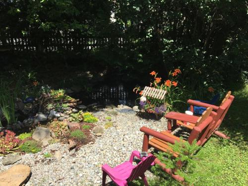 a garden with two wooden chairs and a bench at À Amour et Amitié in Magog-Orford