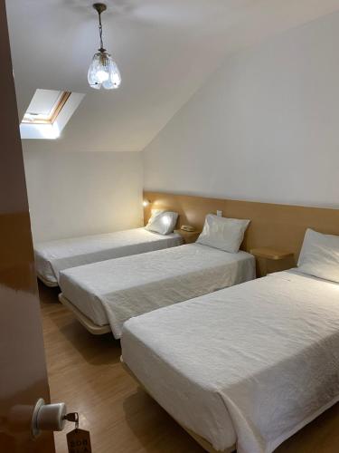 three beds in a hotel room with a window at Guesthouse Lusa Atenas in Coimbra