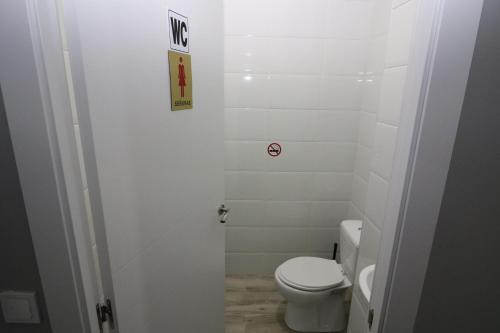 a bathroom with a toilet and a sign on the wall at Madrid Downtown Hostel in Madrid