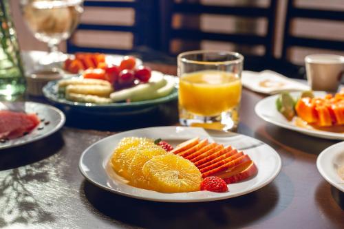a table with plates of fruit and a glass of orange juice at H+ Hotel in Dourados