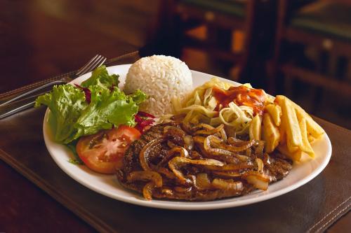 a plate of food with rice and meat and french fries at H+ Hotel in Dourados