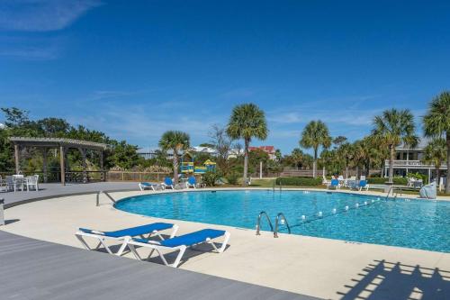 a swimming pool with blue chairs and palm trees at Nautical Watch on Harbor Island in Oceanmarsh Subdivision