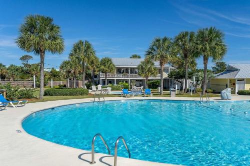 a swimming pool with palm trees and a house in the background at Nautical Watch on Harbor Island in Oceanmarsh Subdivision