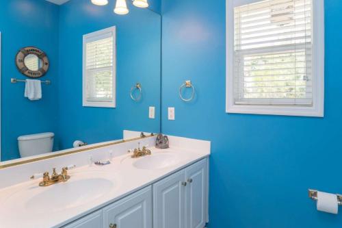 a blue bathroom with two sinks and a mirror at Lloyd's Lodge at Davis Love Dr in Fripp Island