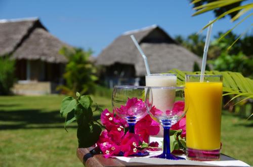 two glasses of orange juice and flowers on a table at Hotel le Lagon in Foulpointe