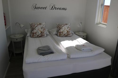 ein weißes Bett mit Handtüchern und Kissen darauf in der Unterkunft Laxhús in Húsavík