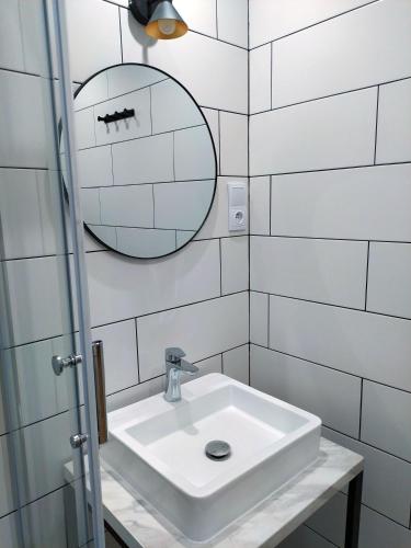 a white bathroom with a sink and a mirror at OficynaApartments in Gliwice