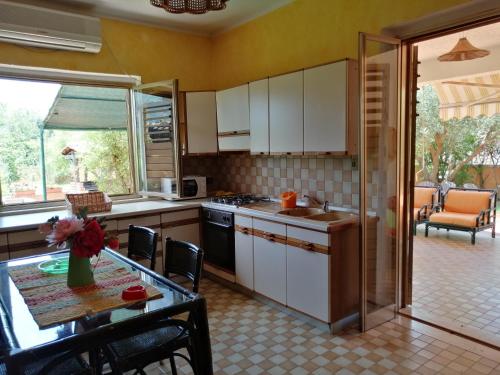 a kitchen with white cabinets and a table and a dining room at Villa Kampia in Capo Vaticano