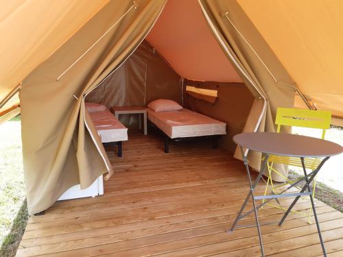 namiot z dwoma łóżkami i stołem w obiekcie Camping de la minière w mieście Forges-les-Eaux