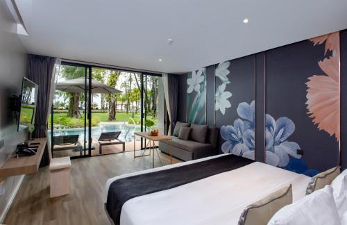 a bedroom with a large bed and a living room at La Flora Khao Lak - SHA Extra Plus in Khao Lak