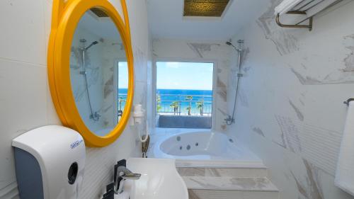 a bathroom with a sink and a mirror and a tub at Sea City Devran Hotel & Spa in Antalya